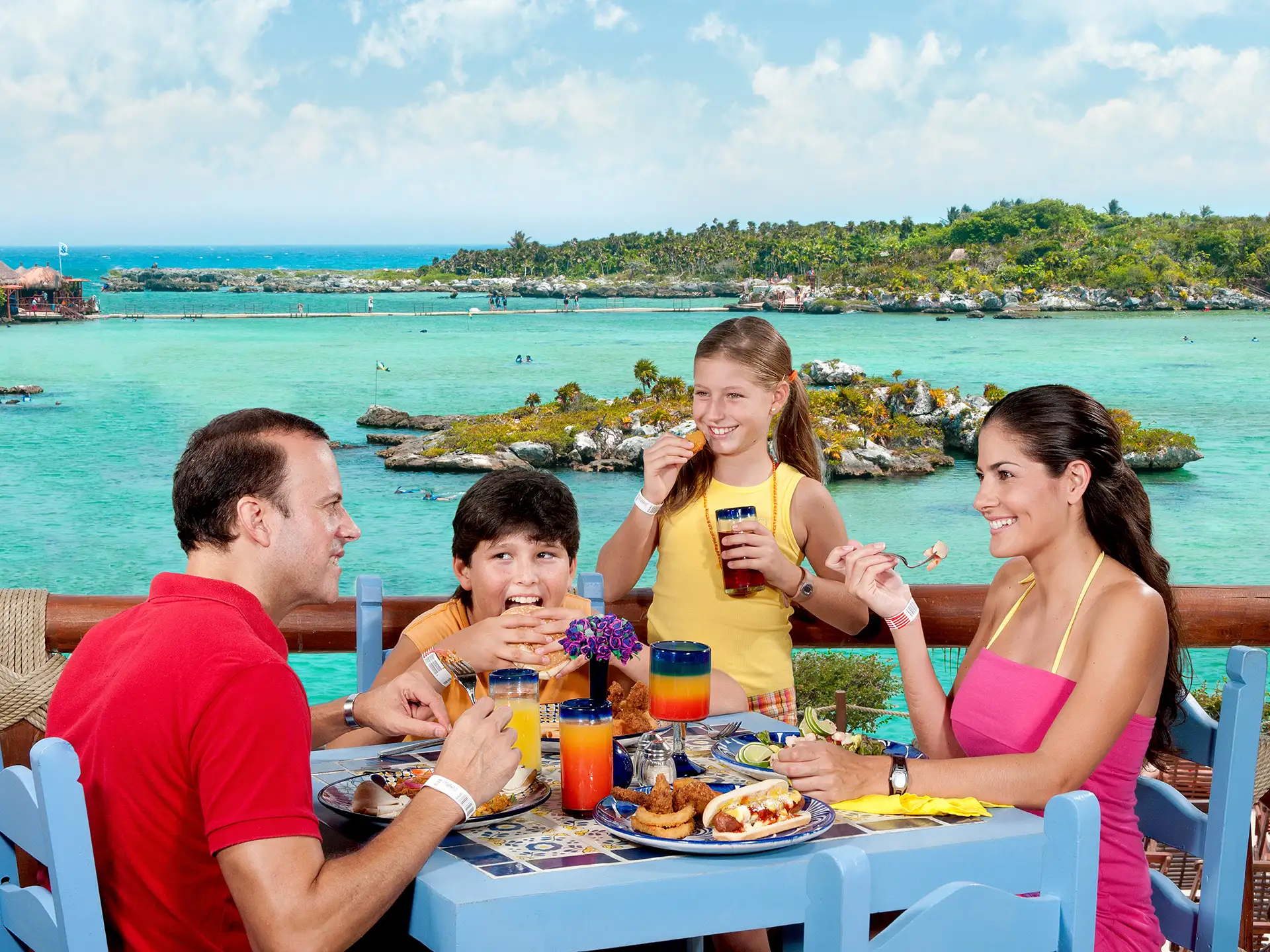 Family enjoying buffet dining with a tropical view at Xel-Há, surrounded by turquoise water and lush scenery.
